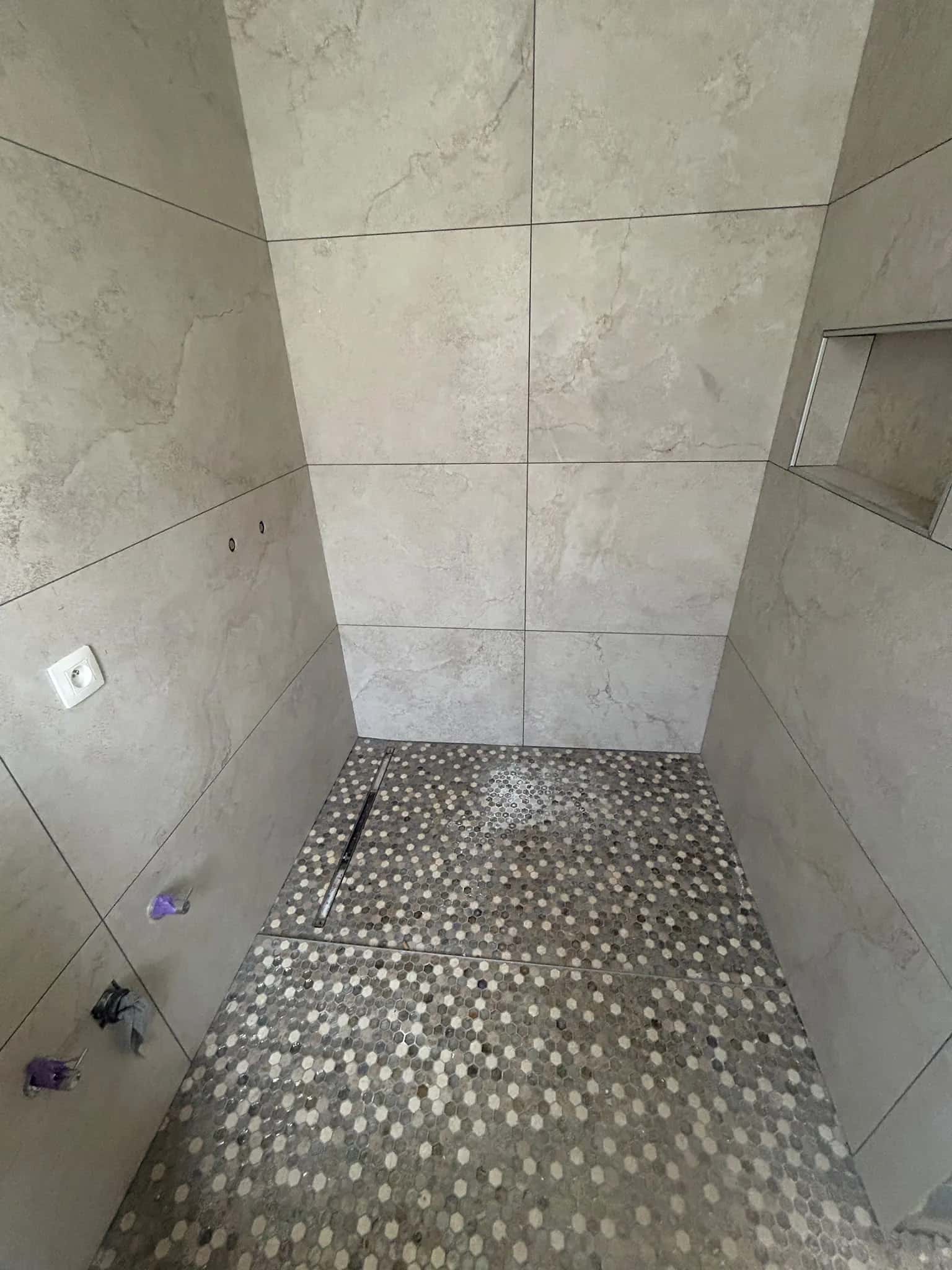 Douche à l'italienne au sol en mosaïque hexagonale, niche encastrée entre les grands formats