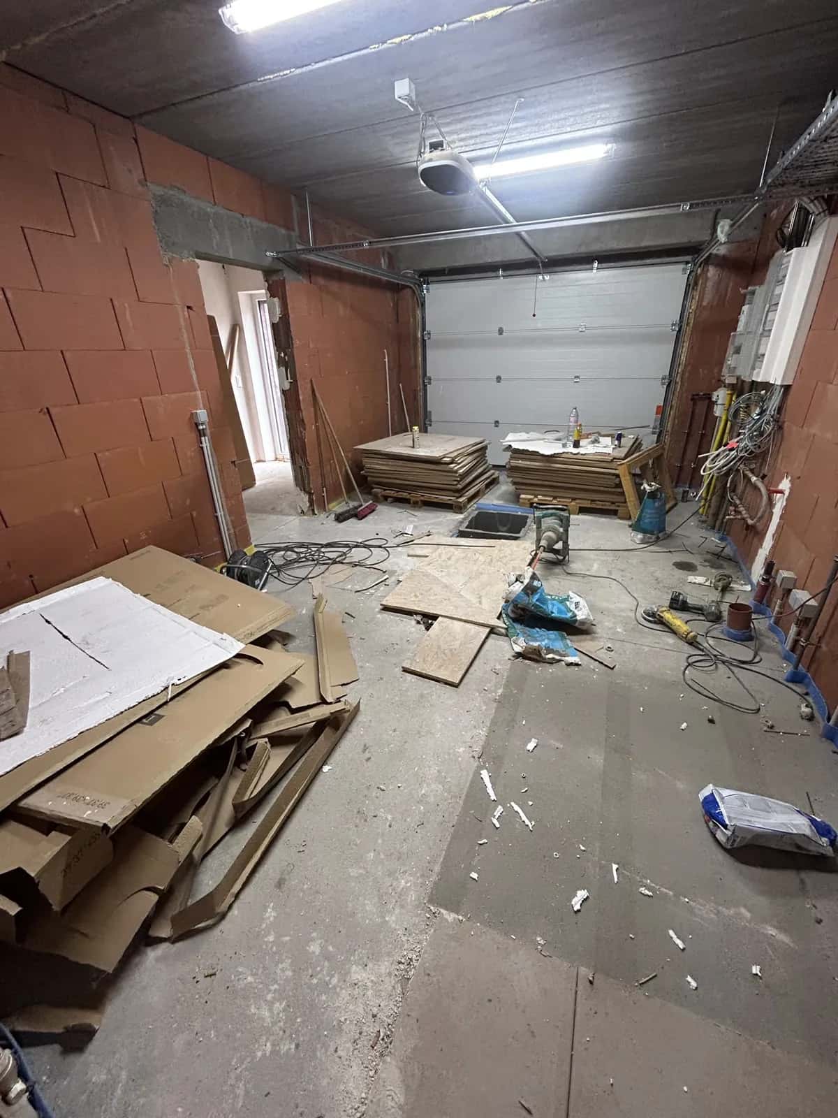 Le garage avant la pose : dalle béton, palettes de carreaux et outillage