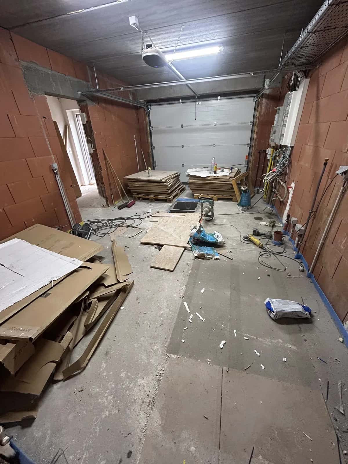 Chantier du garage en préparation, emballages dégagés le long du mur