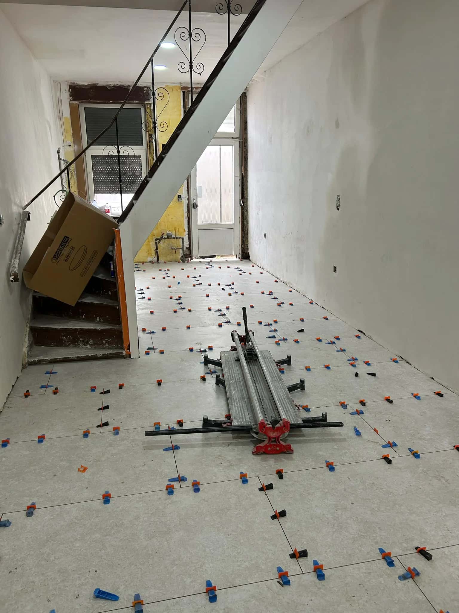 Pose en cours au pied de l'escalier, niveleurs sur chaque joint