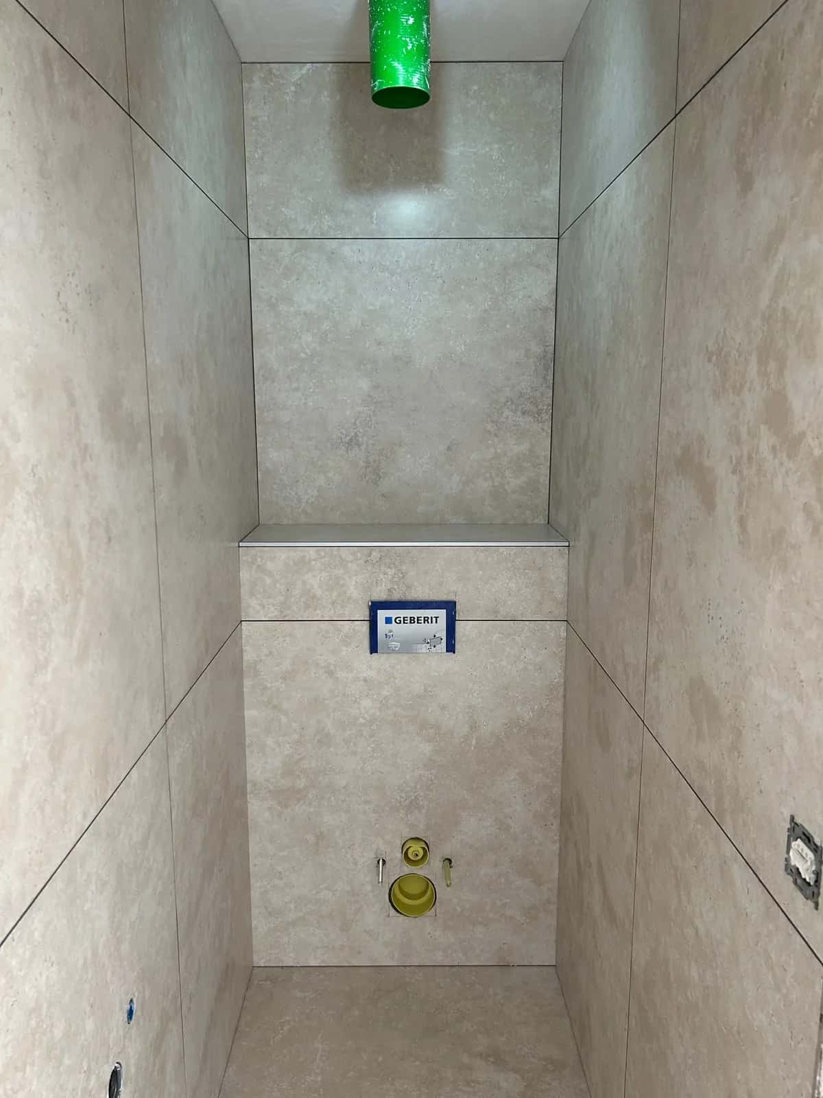 Niche du toilette suspendu habillée du même grand format, du sol au plafond