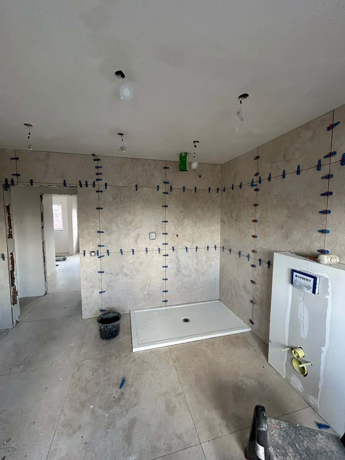 Salle de bain carrelée en grand format effet béton, vue d'ensemble pendant la pose