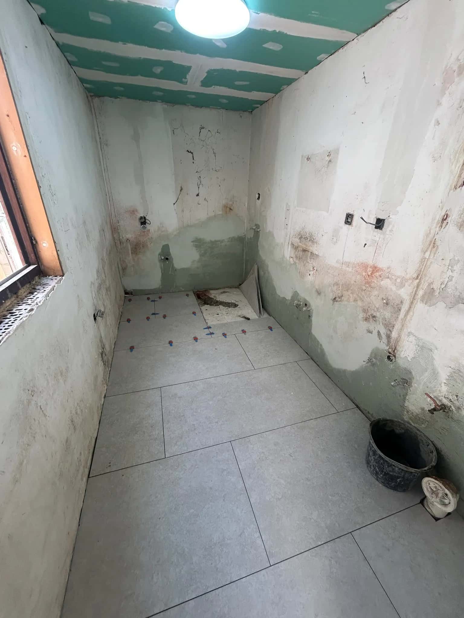 La salle de bain avant la pose murale : murs nus et étanchéité au pied des murs