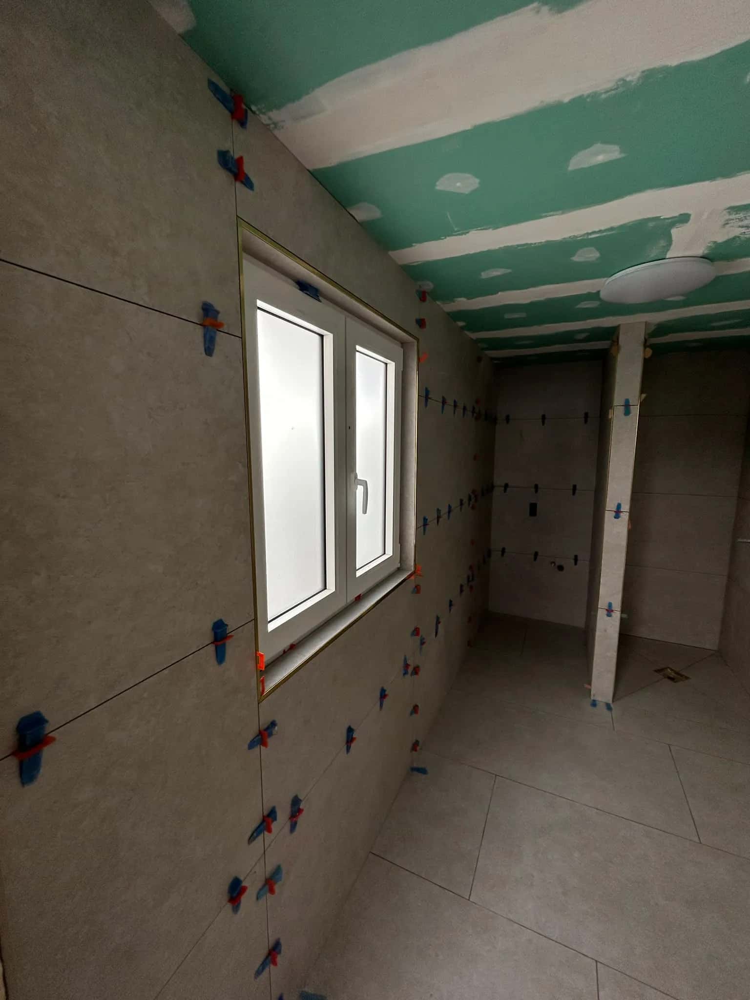 Grands formats muraux posés autour de la fenêtre de la salle de bain