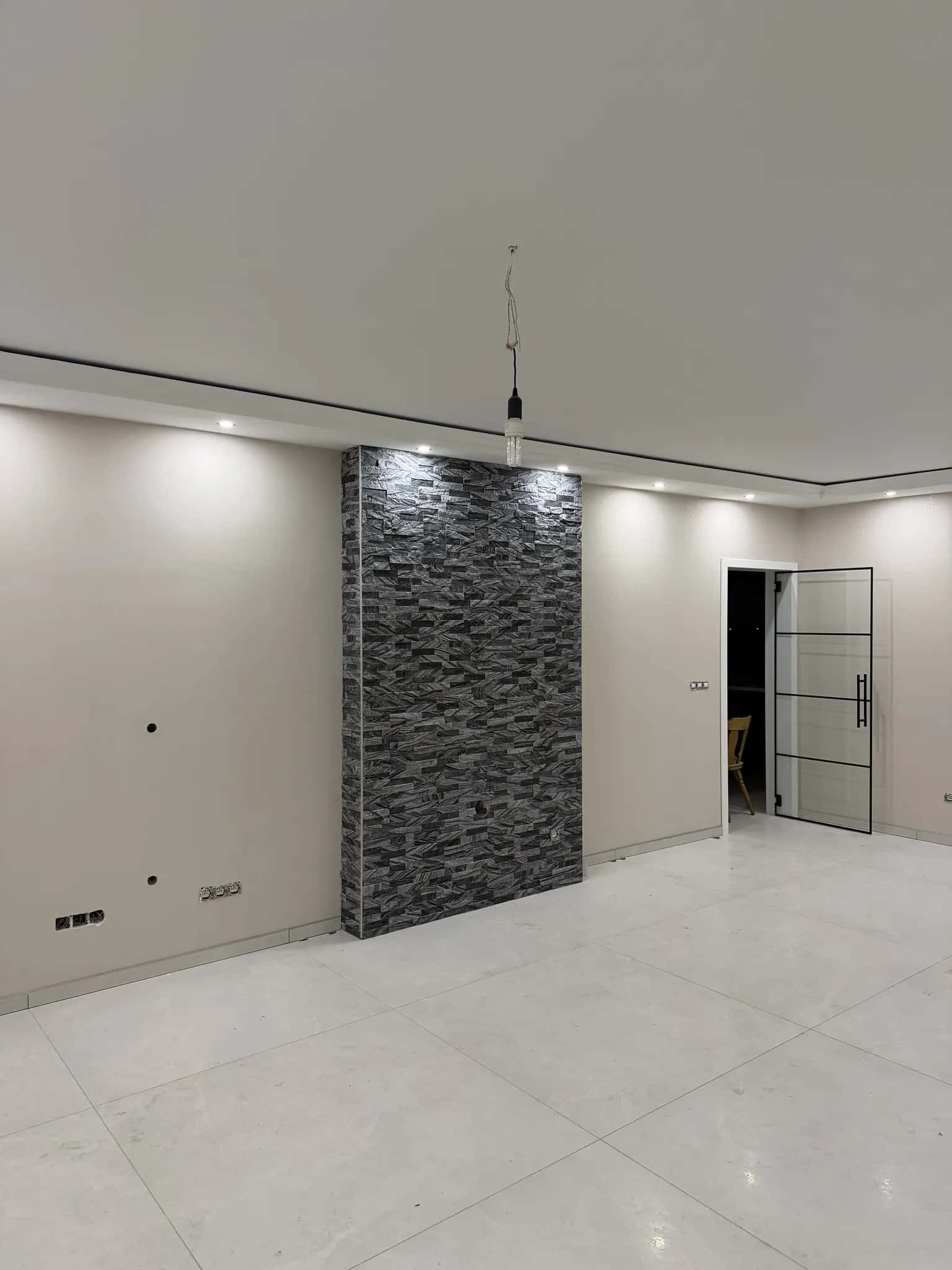 Mur du séjour habillé de parement pierre gris anthracite, à côté de la porte vitrée