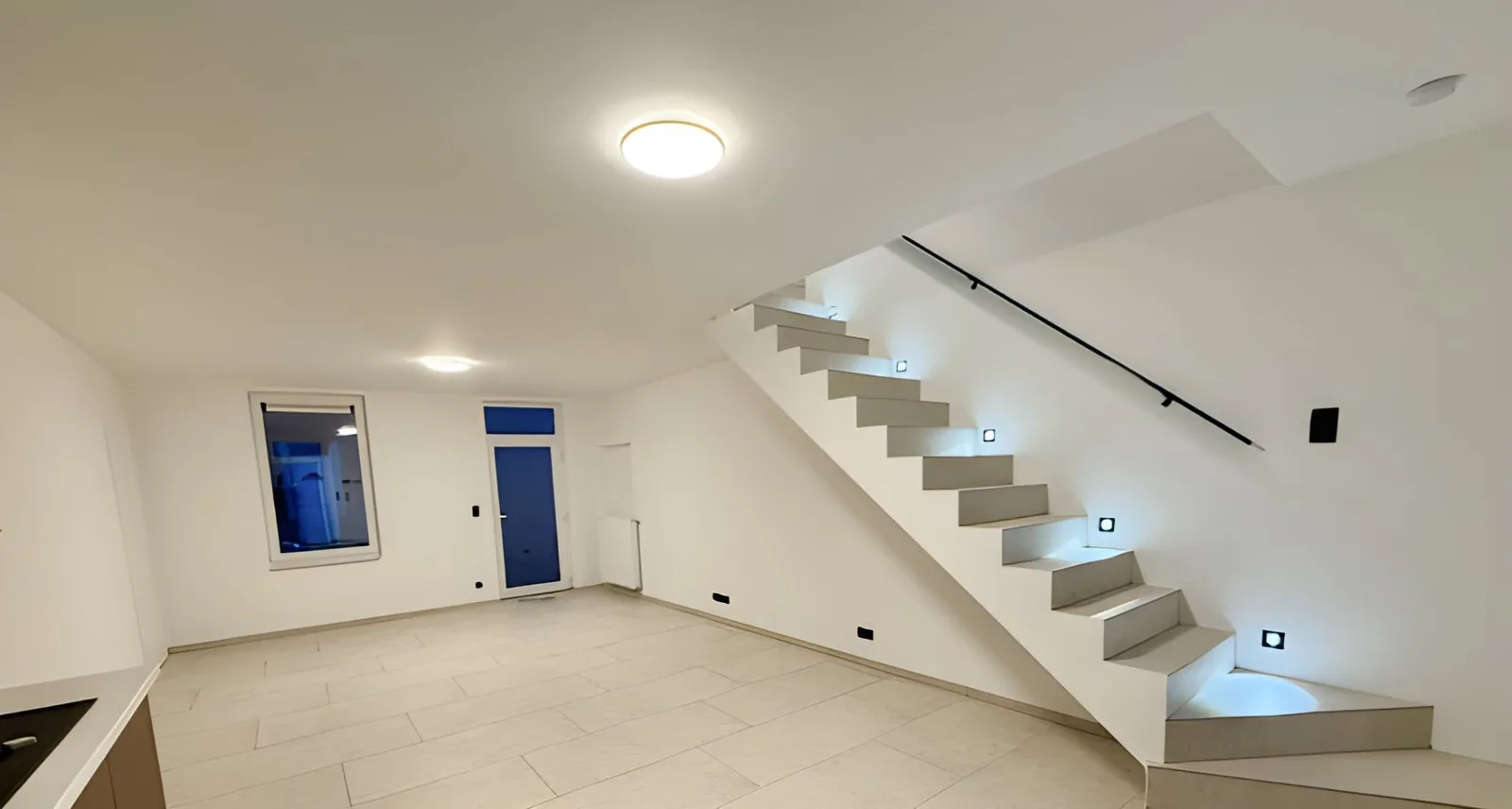 Séjour terminé au sol carrelé, avec son escalier éclairé par des spots, photo publiée par le client sur Google