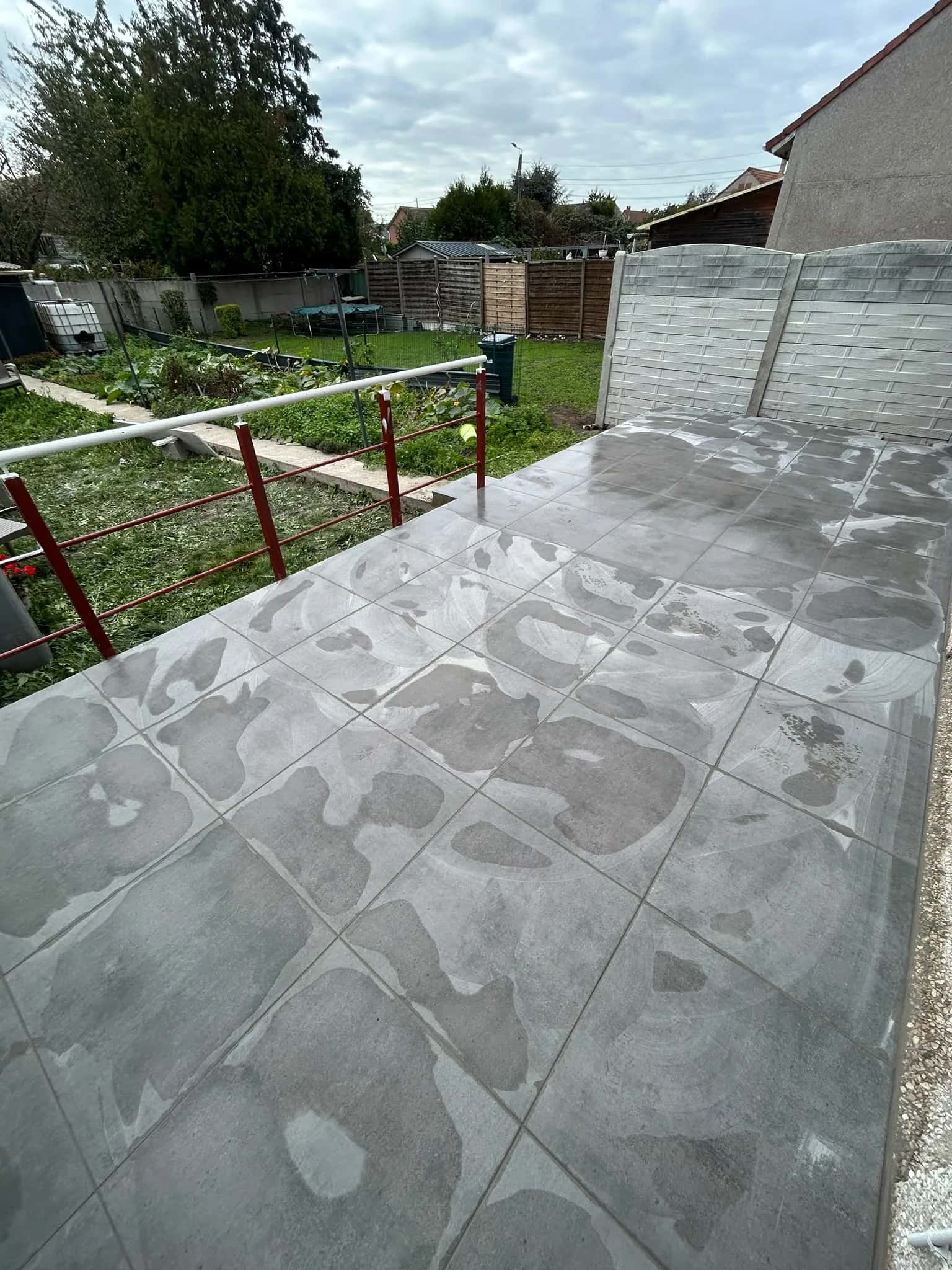 La même terrasse après la pluie, carrelage mouillé sur toute la longueur