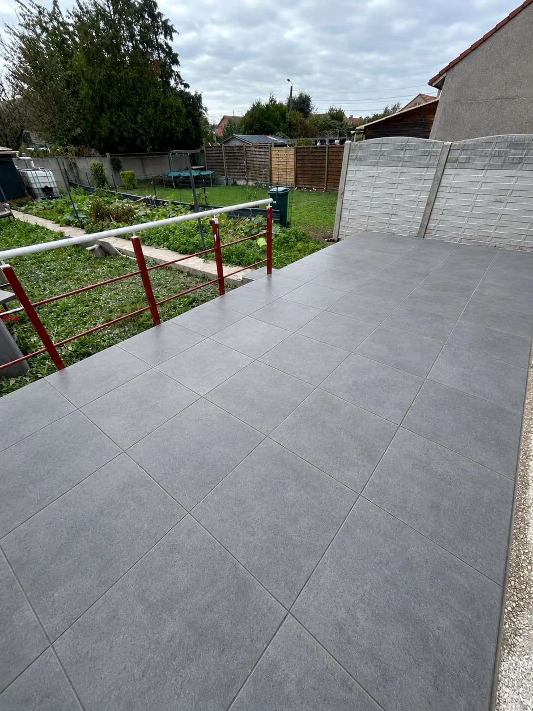 Terrasse carrelée gris foncé par Km pose, garde-corps au-dessus du jardin