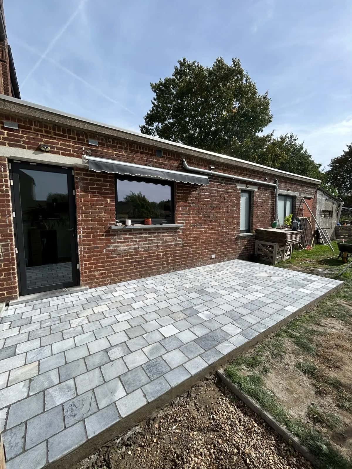 Terrasse en pavés vue depuis le jardin, bordure droite au-dessus de la pelouse