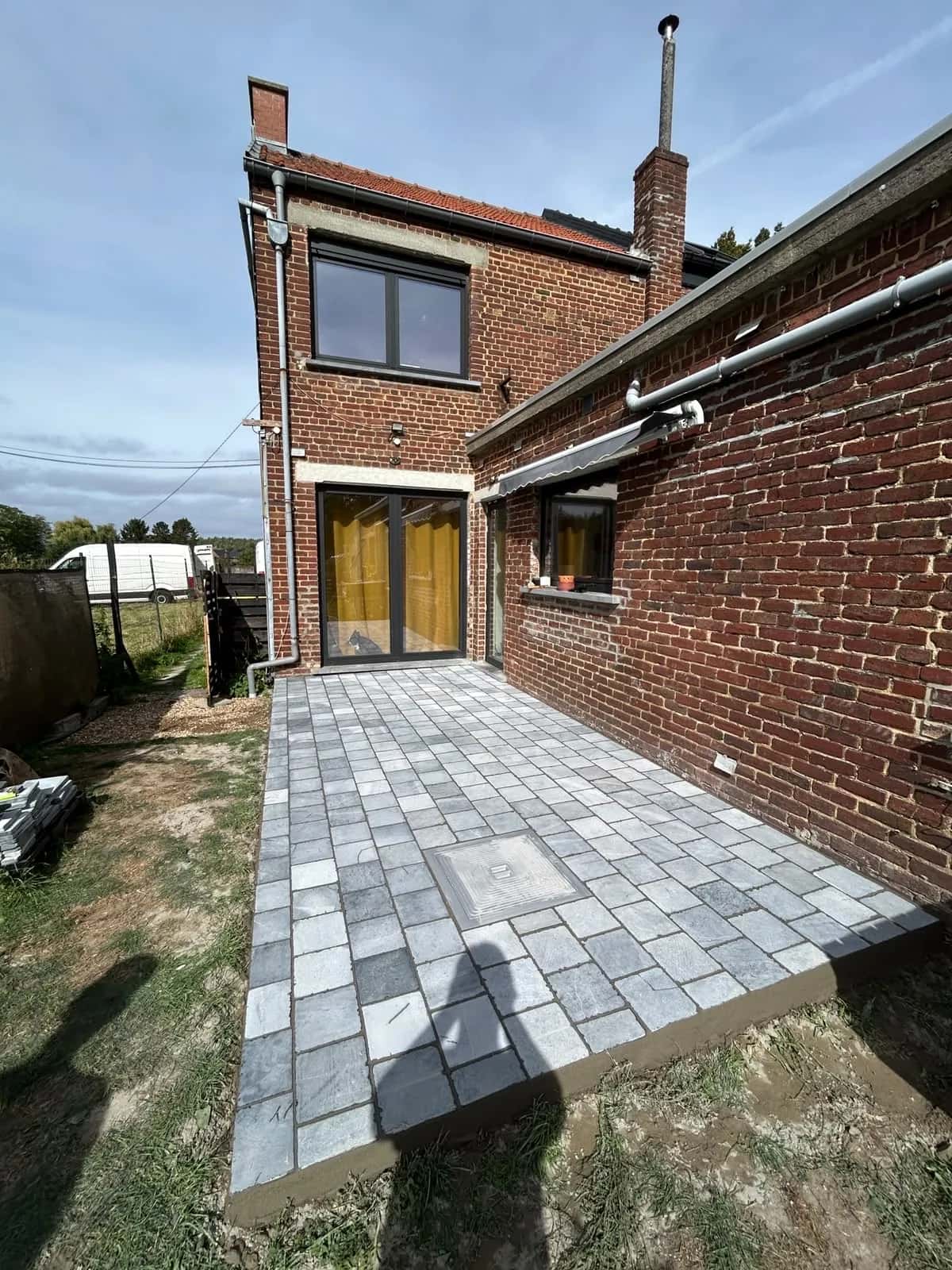 Terrasse en pavés dans l'angle de la maison, bordure franche côté jardin