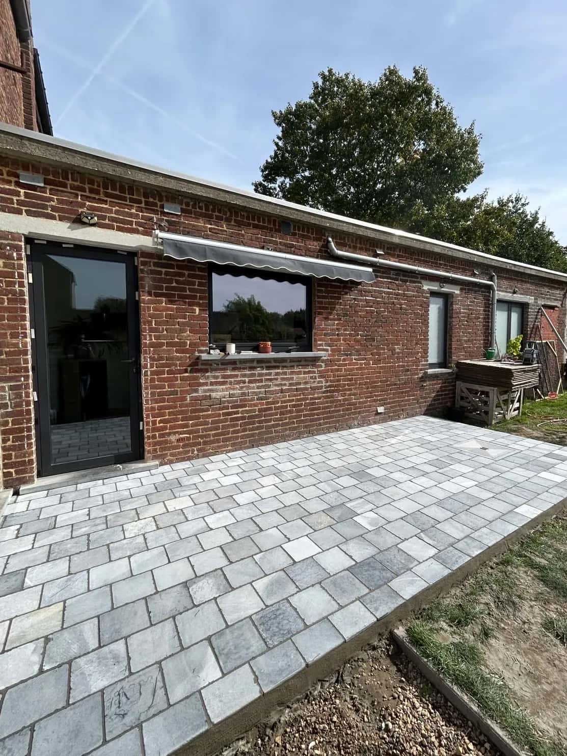Même vue après la pose : terrasse en pavés effet pierre jusqu'à la bordure