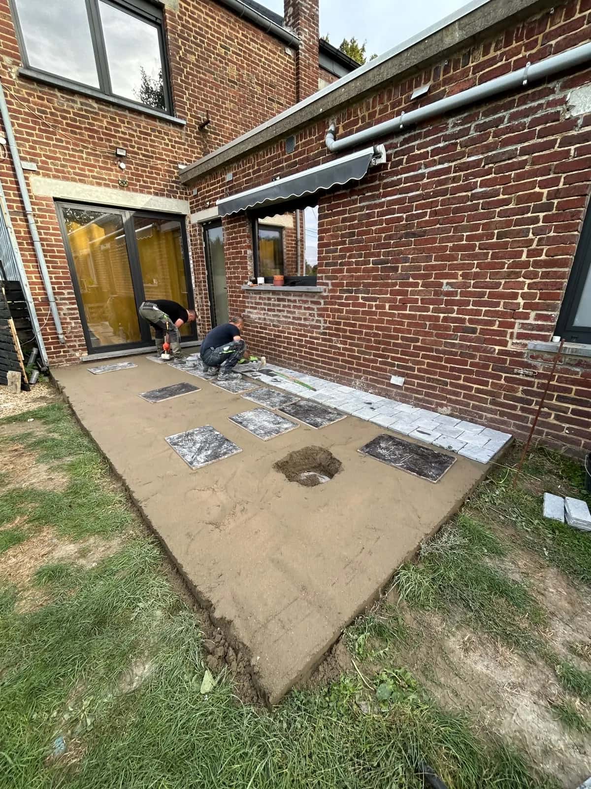 Dalle béton préparée et pavés répartis sur la surface avant la pose