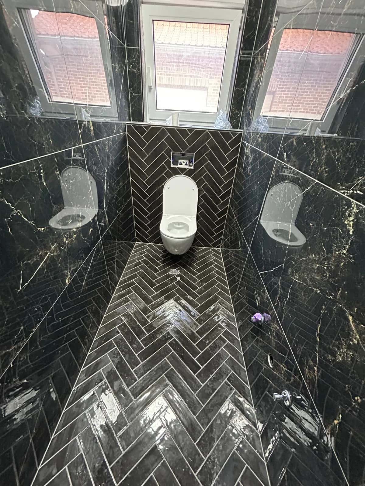 Toilettes en marbre noir veiné, chevron au sol et sur le mur du fond, cuvette suspendue